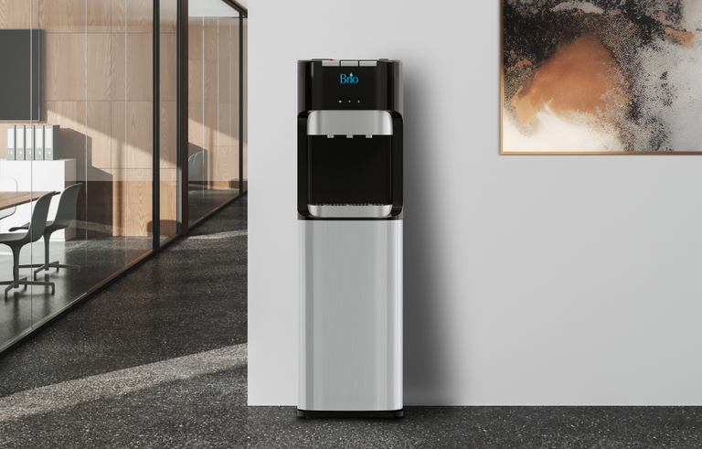 A modern water cooler with a digital display stands against a white wall in a stylish office, near a glass partition and an abstract painting.